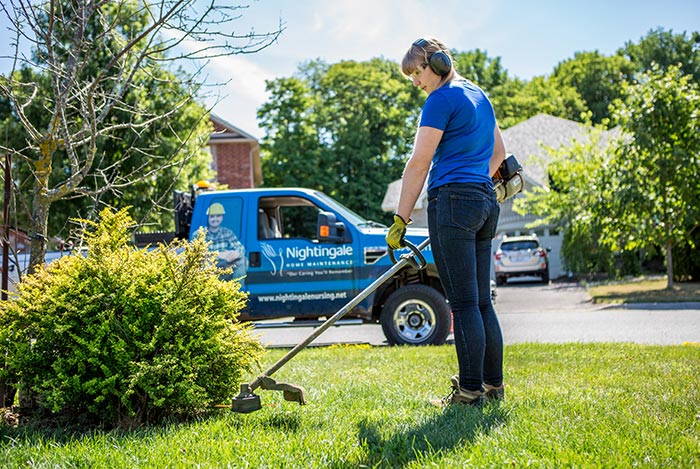 Woman trimming grass with a weedwhacker.