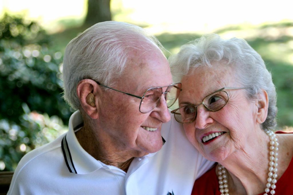 Elderly woman laying head on elderly mans shoulder