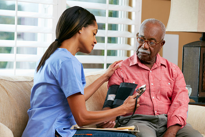 Female Nurse Visiting Senior Male Patient At Home