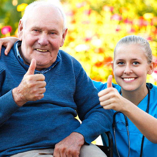 Elderly man and Caregiver smiling with their thumbs up